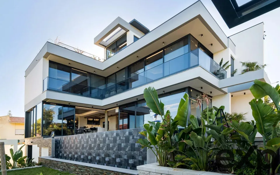 Moradia contemporânea de três pisos no Golfe do Estoril, com amplos envidraçados, varandas em vidro e jardim tropical